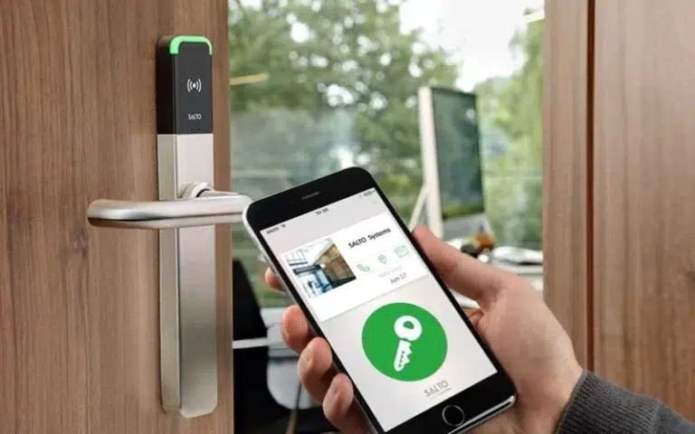 A hand with a mobile entry key against a Salto door access control